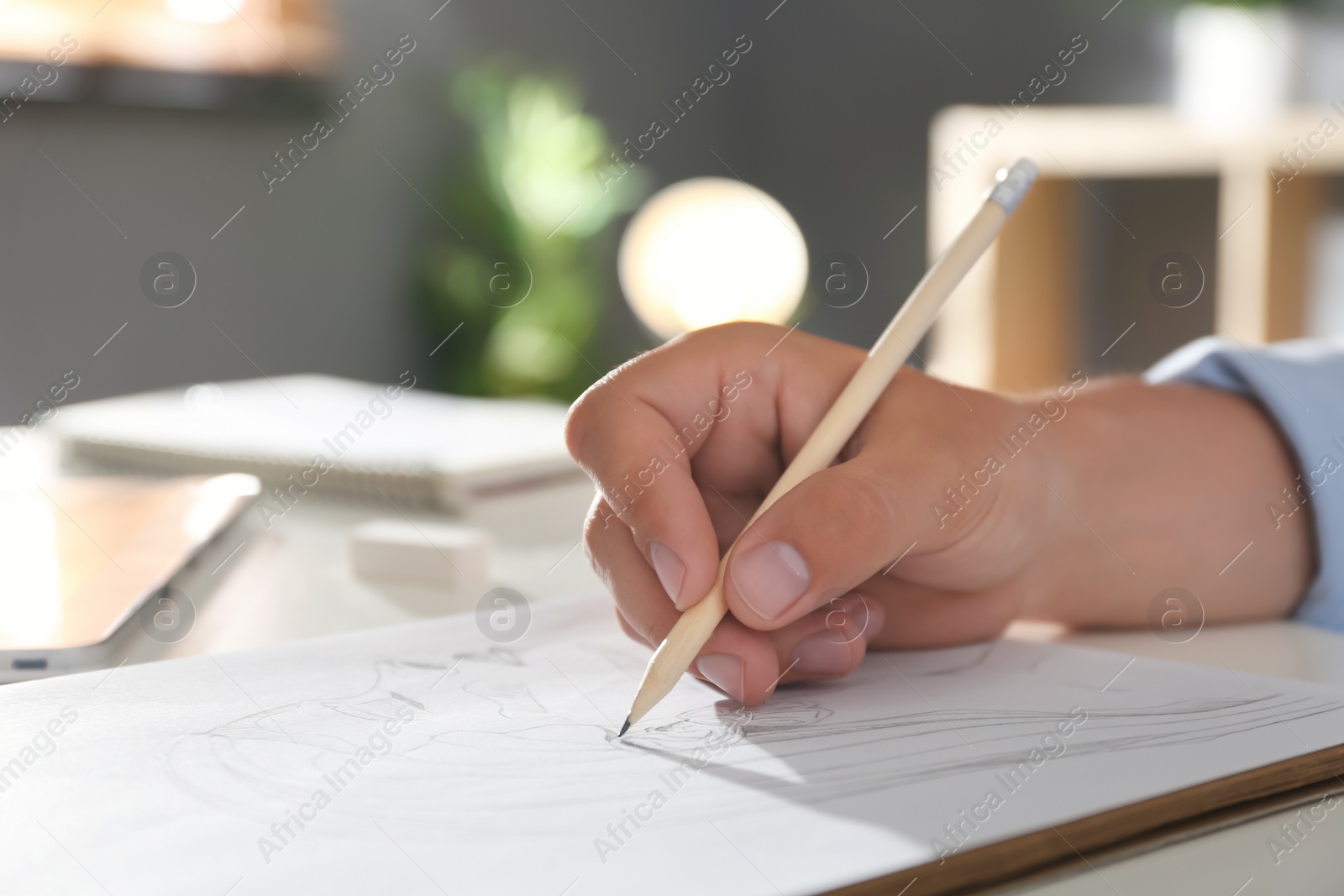 Photo of Man drawing portrait with pencil in notepad at table, closeup