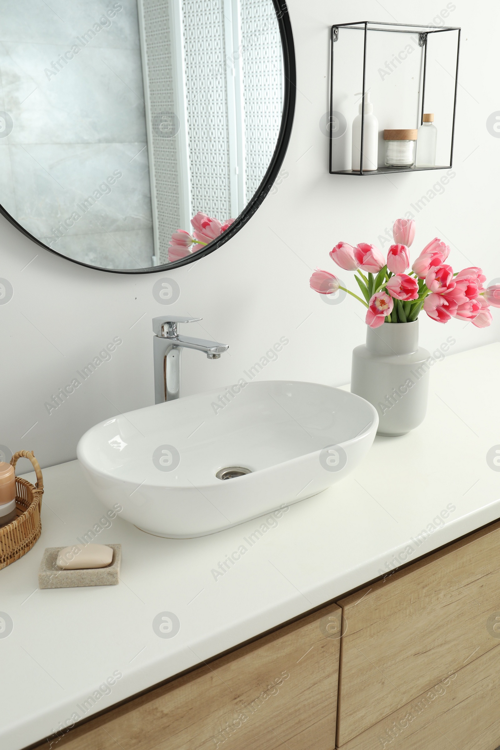 Photo of Vase with beautiful pink tulips near sink in bathroom