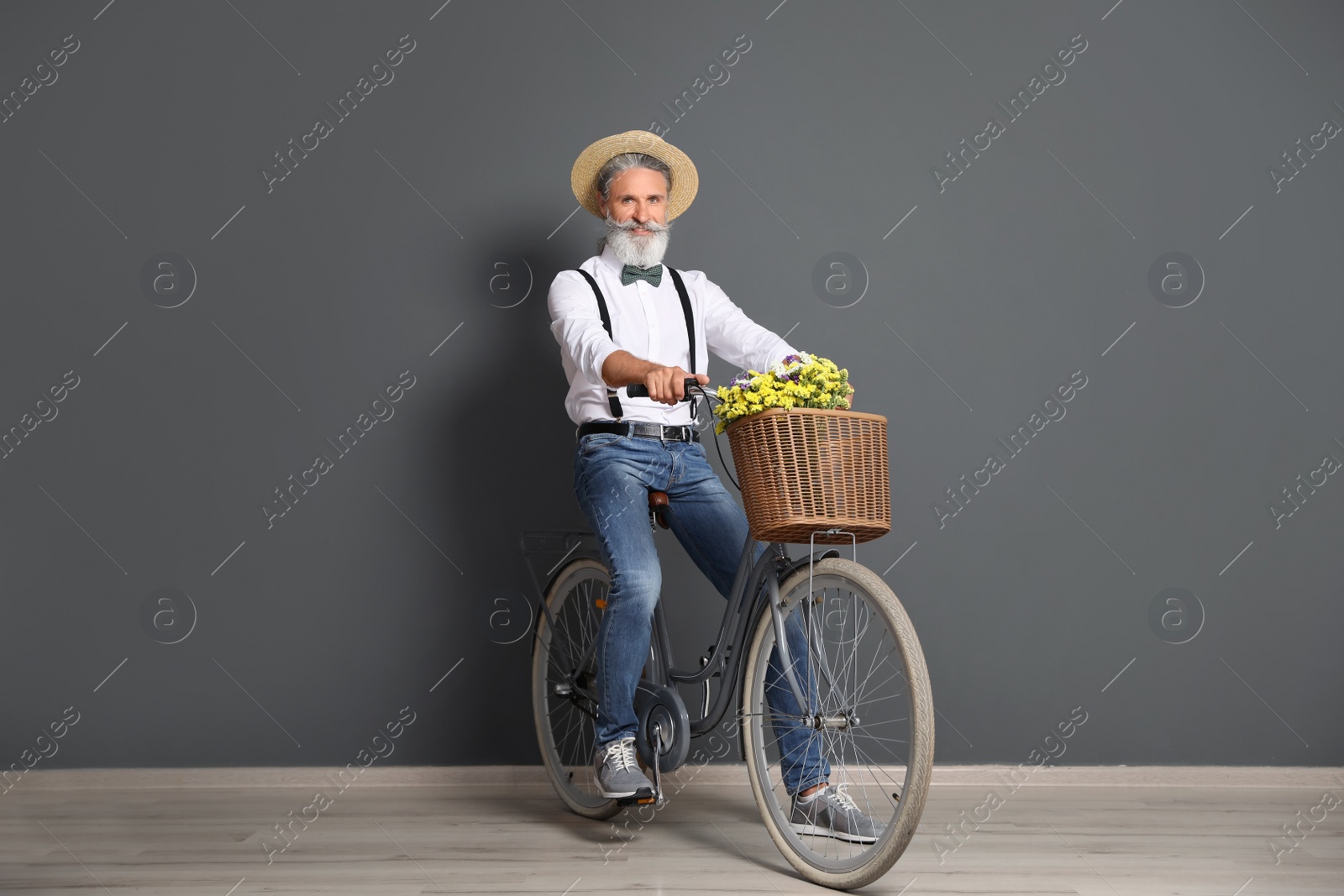 Photo of Portrait of handsome mature man with bicycle near color wall