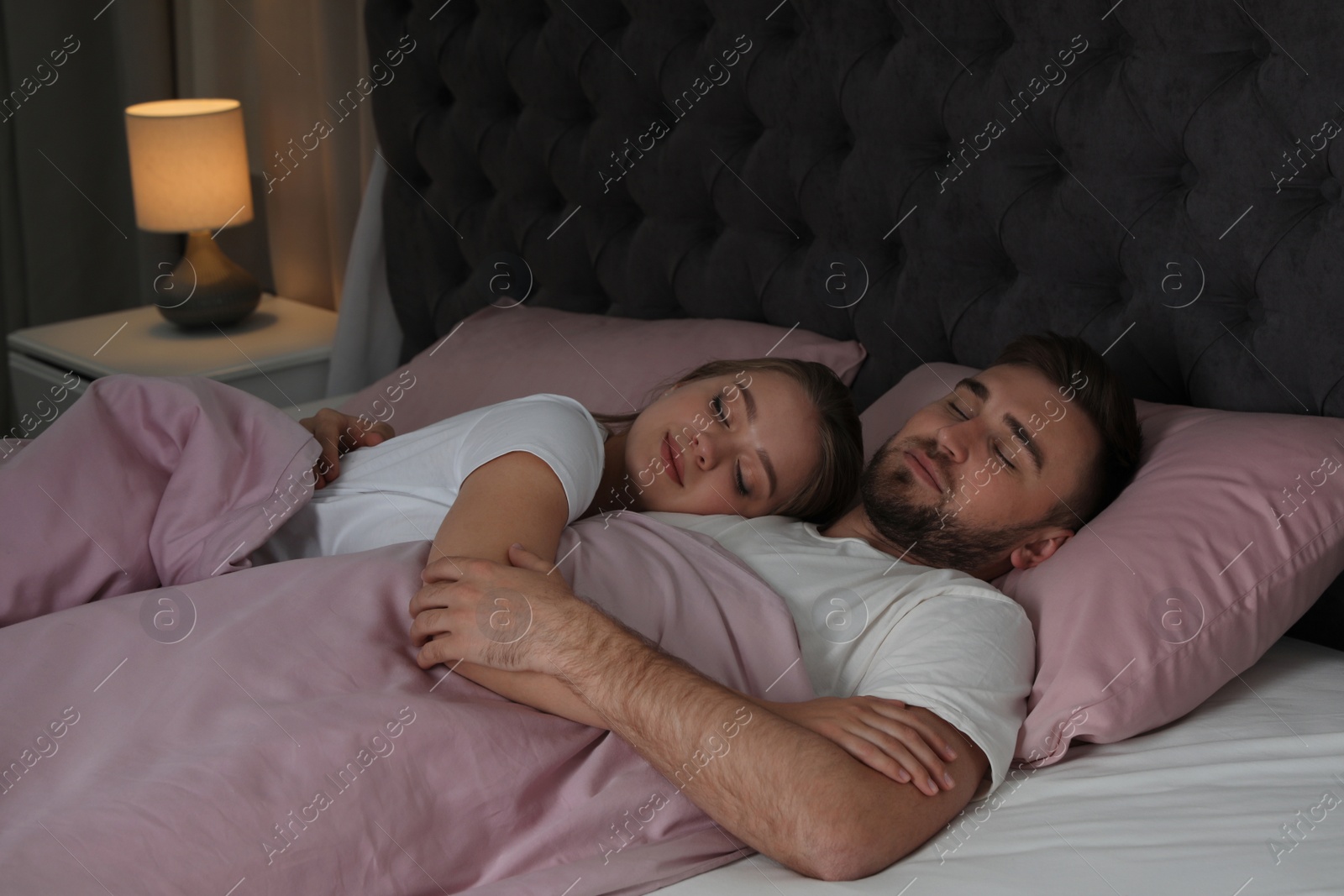 Photo of Young couple sleeping together in bed at nighttime