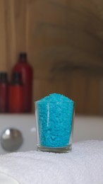 Photo of Glass with sea salt and fluffy towel on bath