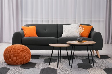 Photo of Comfortable sofa, pouf and coffee table in stylish room. Interior design