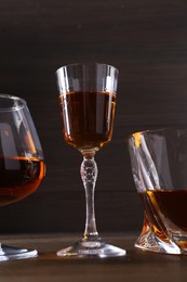 Different delicious liqueurs in glasses on wooden table