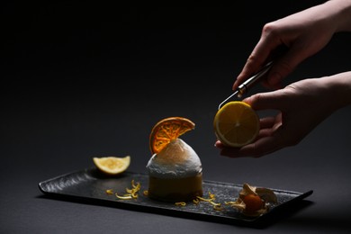 Photo of Food stylist creating beautiful composition with delicious dessert on black background, closeup