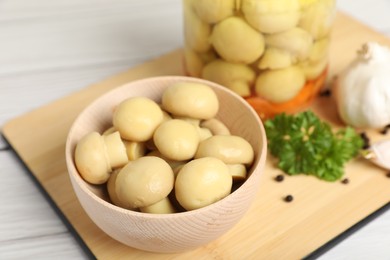 Bowl with delicious pickled mushrooms on white wooden table