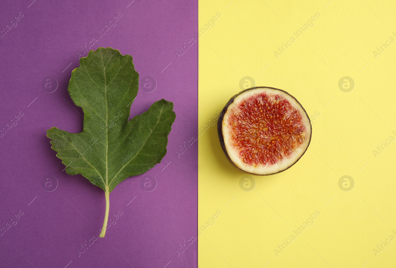 Photo of Green leaf and cut fig on color background, flat lay