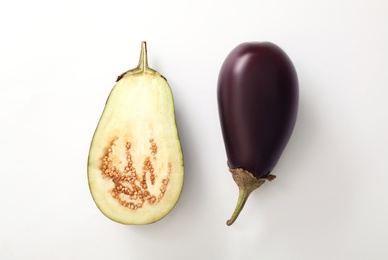 Photo of Cut and whole raw ripe eggplants on white background, flat lay