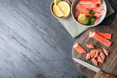 Photo of Flat lay composition with crab sticks, knife and lemon on grey background, space for text