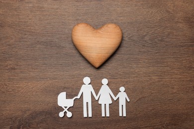 Photo of Paper family cutout and decorative heart on wooden background, flat lay. Insurance concept