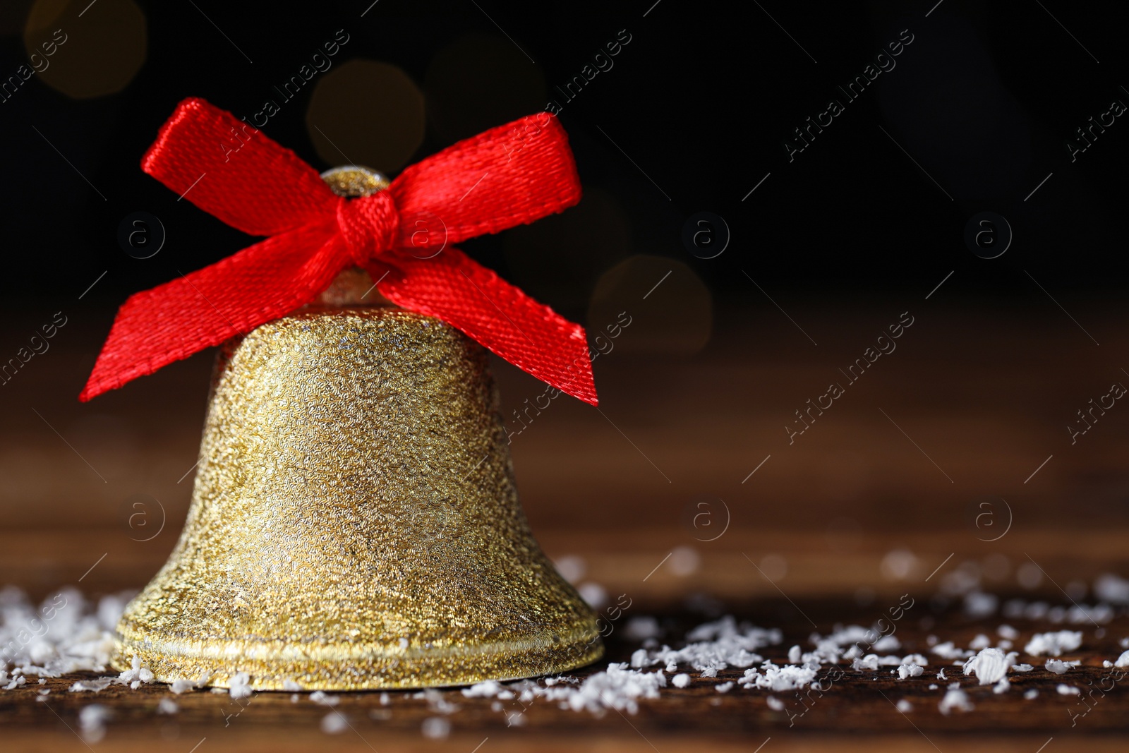 Photo of Bell and artificial snow on table, closeup with space for text. Christmas decor