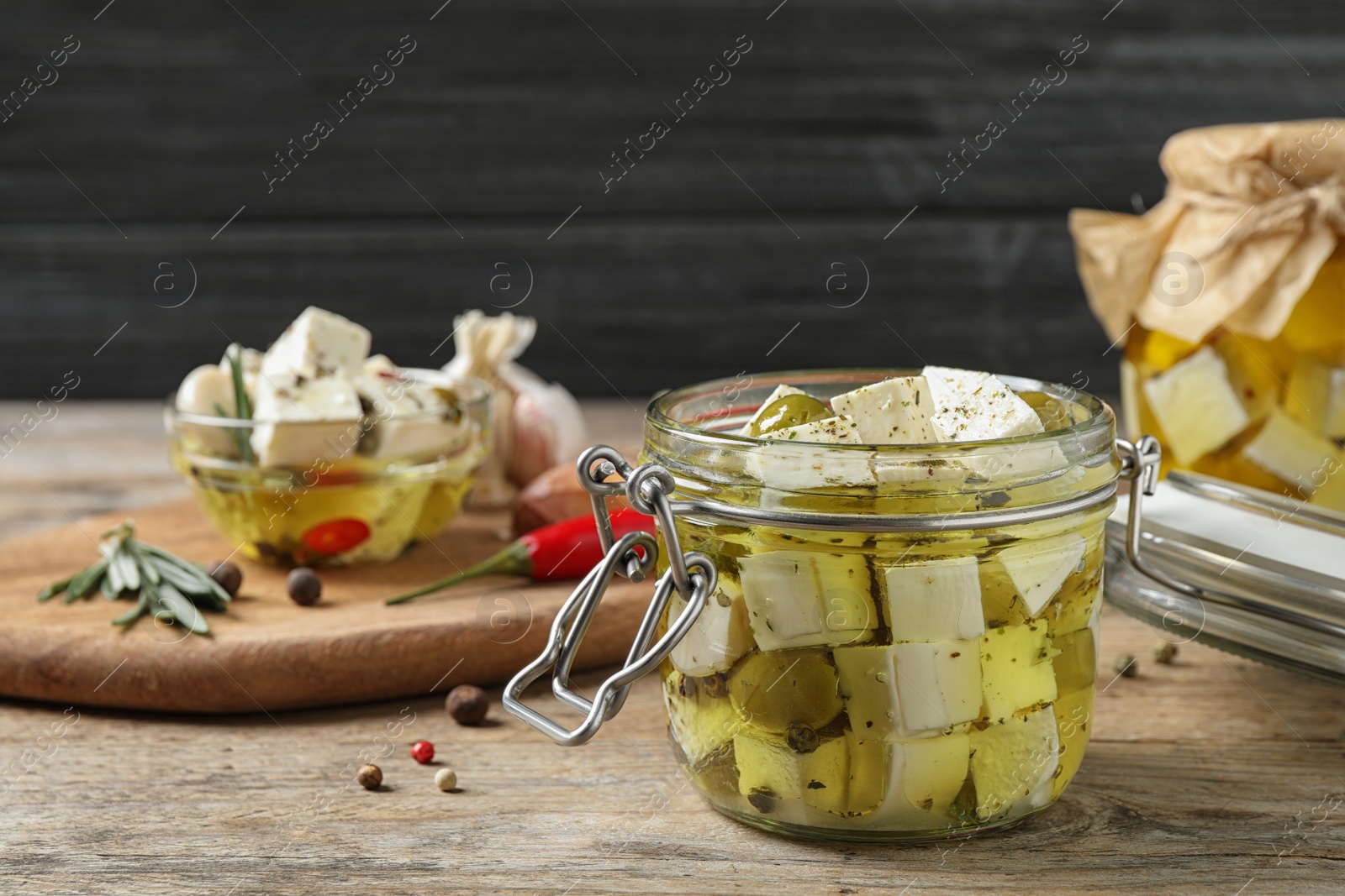 Photo of Composition with pickled feta cheese in jar on wooden table, space for text