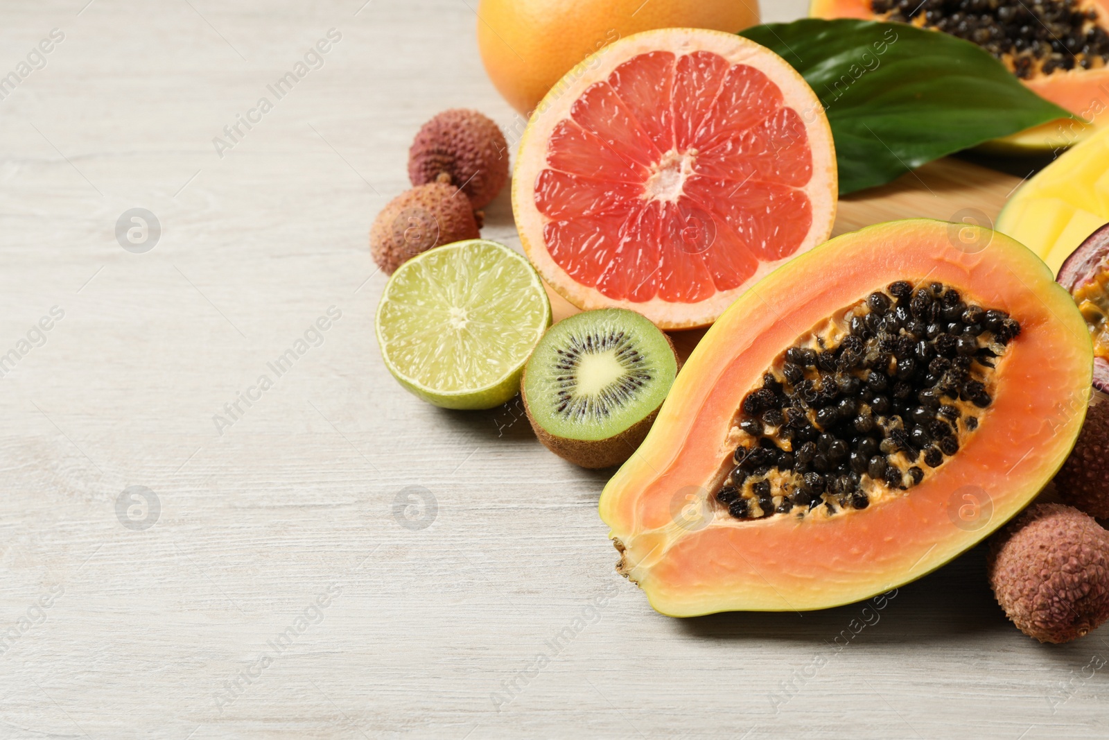 Photo of Fresh ripe papaya and other fruits on white wooden table. Space for text