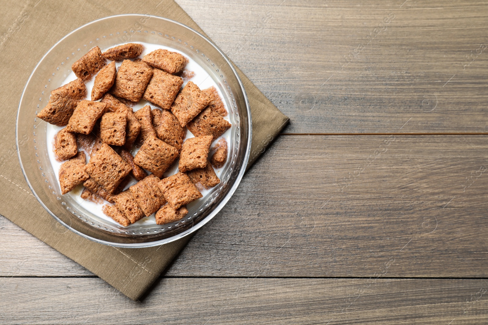 Photo of Tasty corn pads with milk in glass bowl on wooden table, top view. Space for text