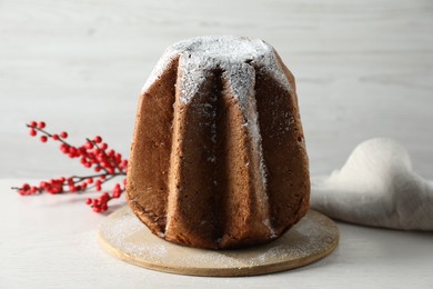 Delicious Pandoro cake decorated with powdered sugar on white wooden table. Traditional Italian pastry