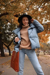 Photo of Young woman wearing stylish clothes in autumn park