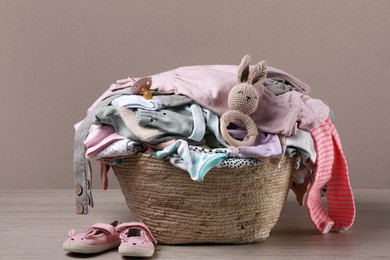 Laundry basket with baby clothes and shoes on wooden table