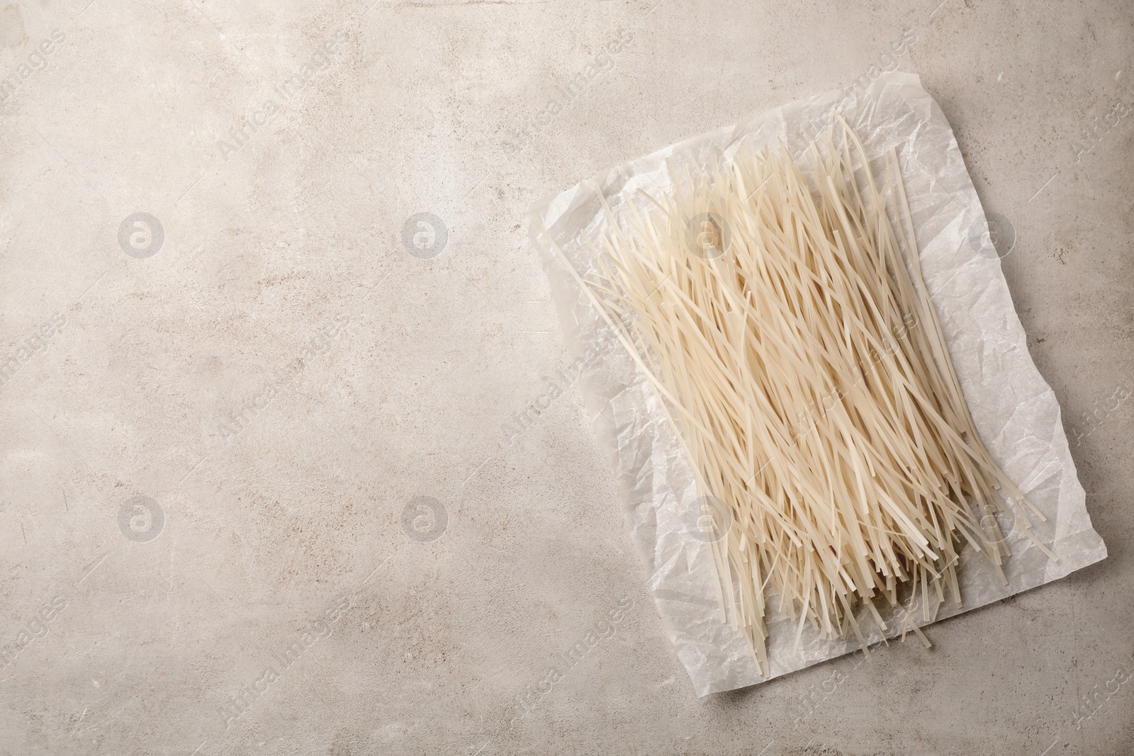 Photo of Raw rice noodles on grey background, top view. Space for text