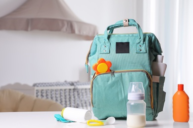 Photo of Maternity backpack with baby accessories on table indoors. Space for text