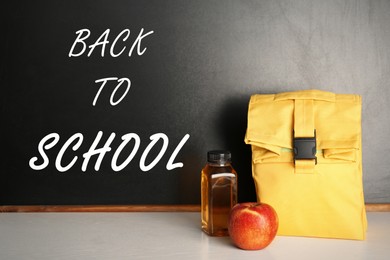 Healthy food for school child in lunch bag on table near blackboard