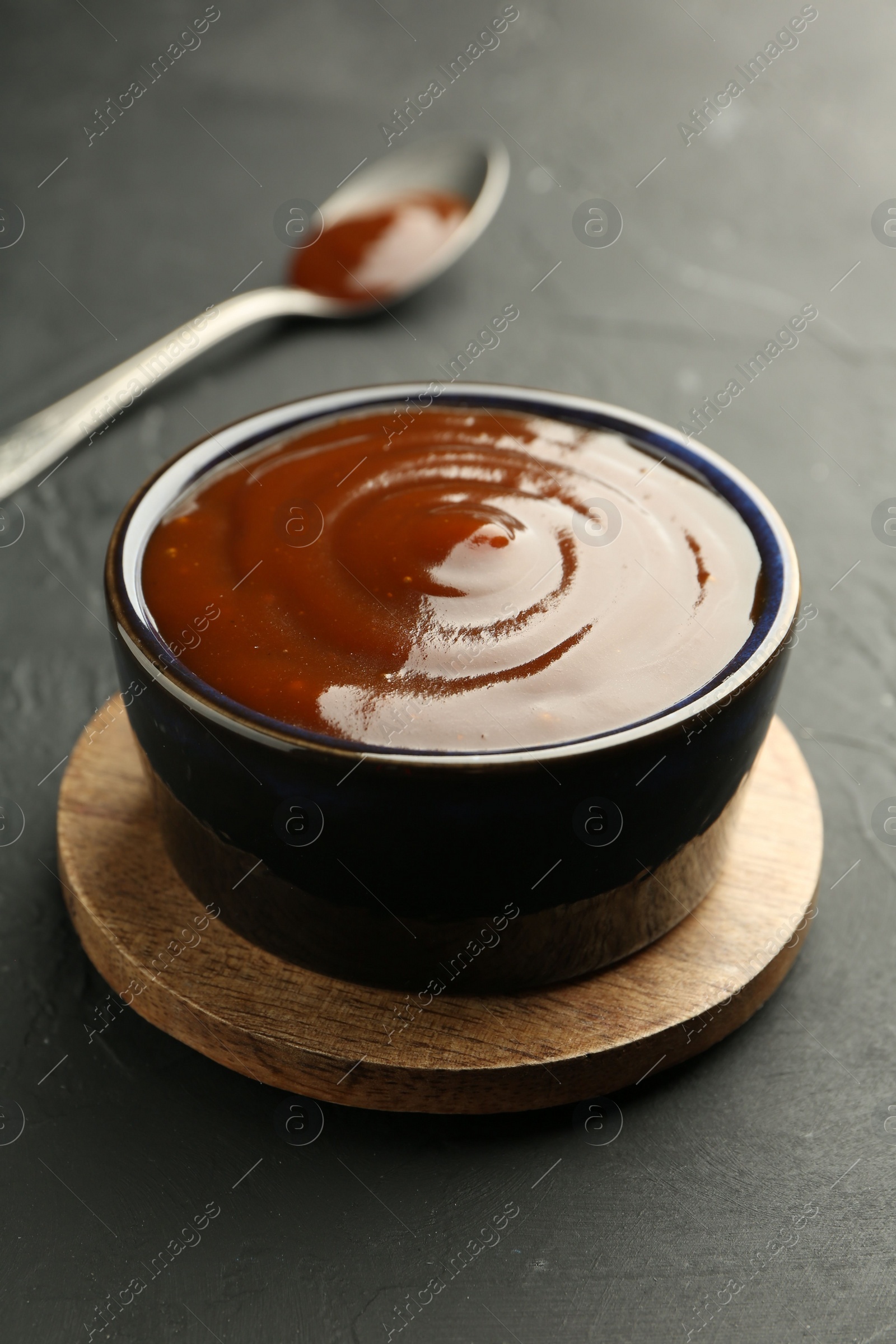 Photo of Tasty barbeque sauce in bowl on dark table, closeup