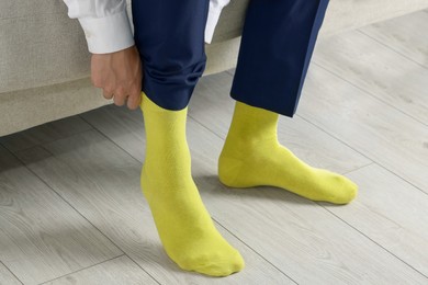 Man putting on yellow socks indoors, closeup