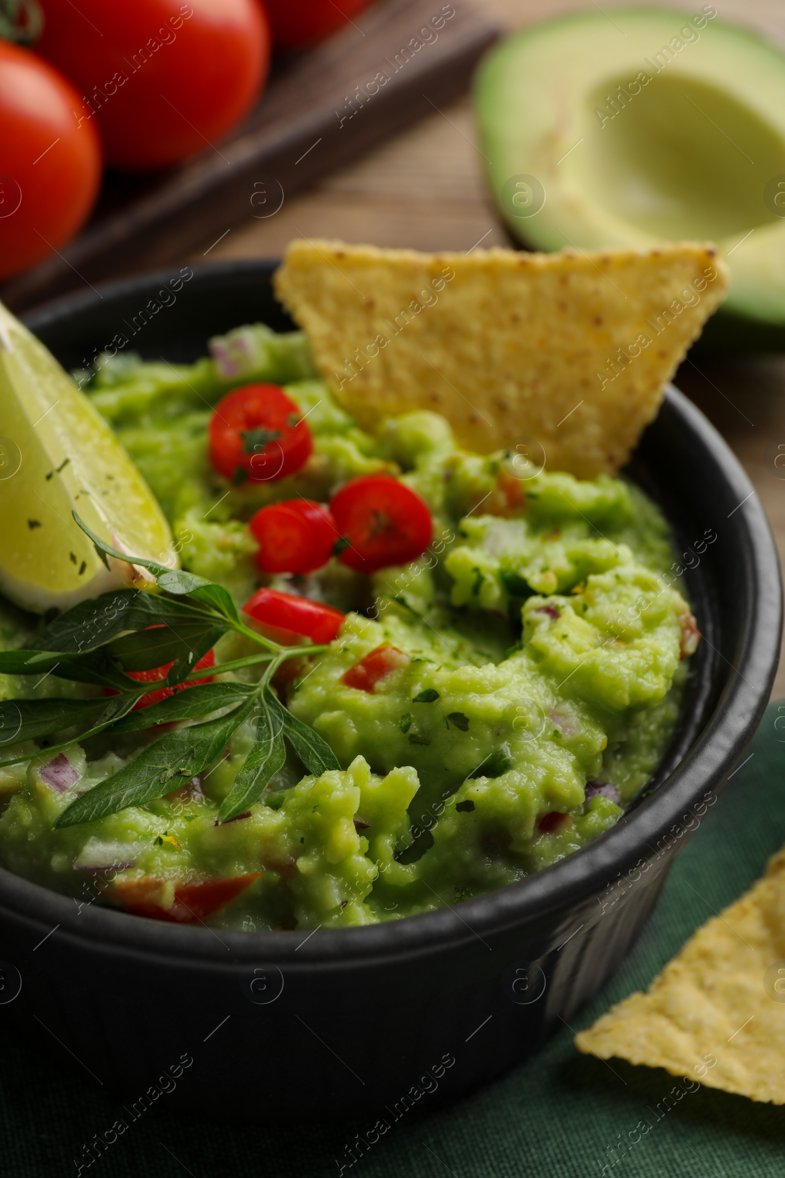 Photo of Delicious guacamole served with nachos chips on table, closeup