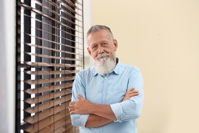 Photo of Portrait of handsome mature man near window with blinds