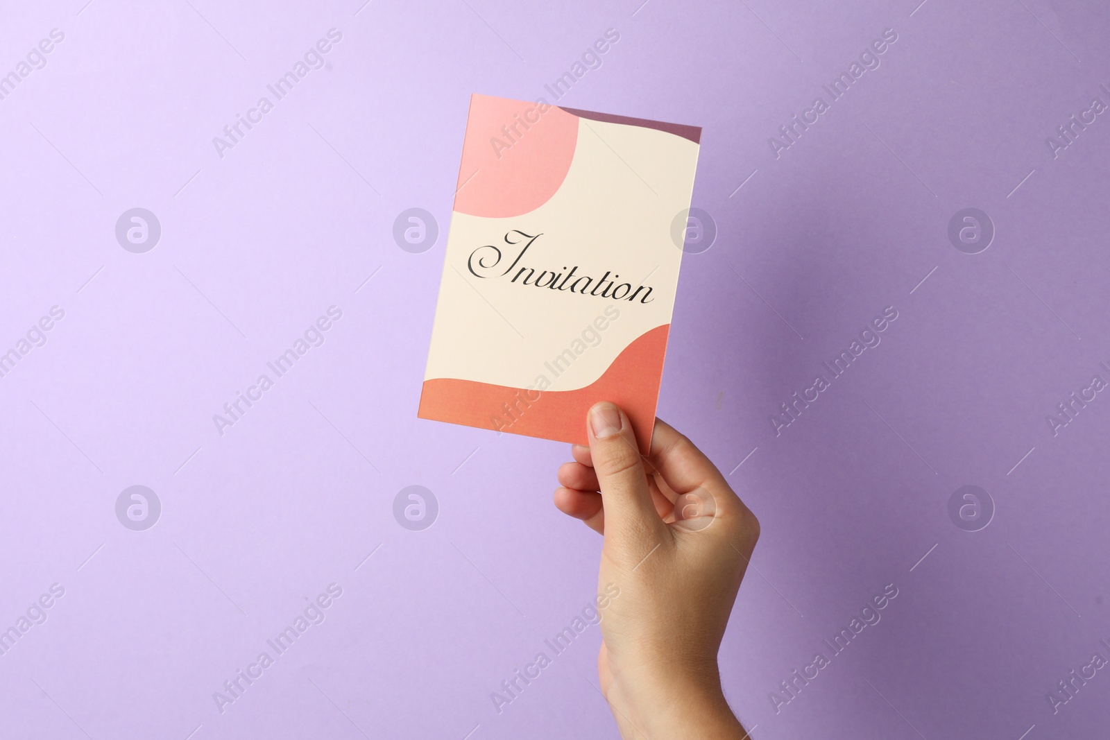 Photo of Woman holding beautiful card with word Invitation on lilac background, closeup