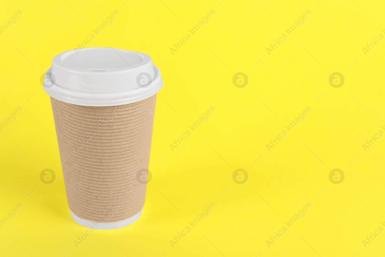 Photo of Paper cup with plastic lid on yellow background, space for text. Coffee to go