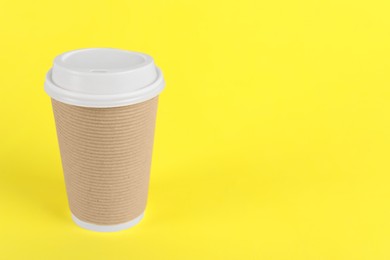 Paper cup with plastic lid on yellow background, space for text. Coffee to go