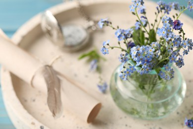 Photo of Beautiful Forget-me-not flowers in vase on tray, closeup