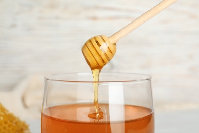 Photo of Sweet honey dripping from dipper into jar, closeup