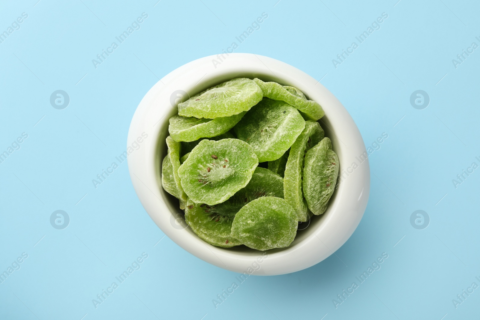 Photo of Bowl with slices of kiwi on color background, top view. Dried fruit as healthy food