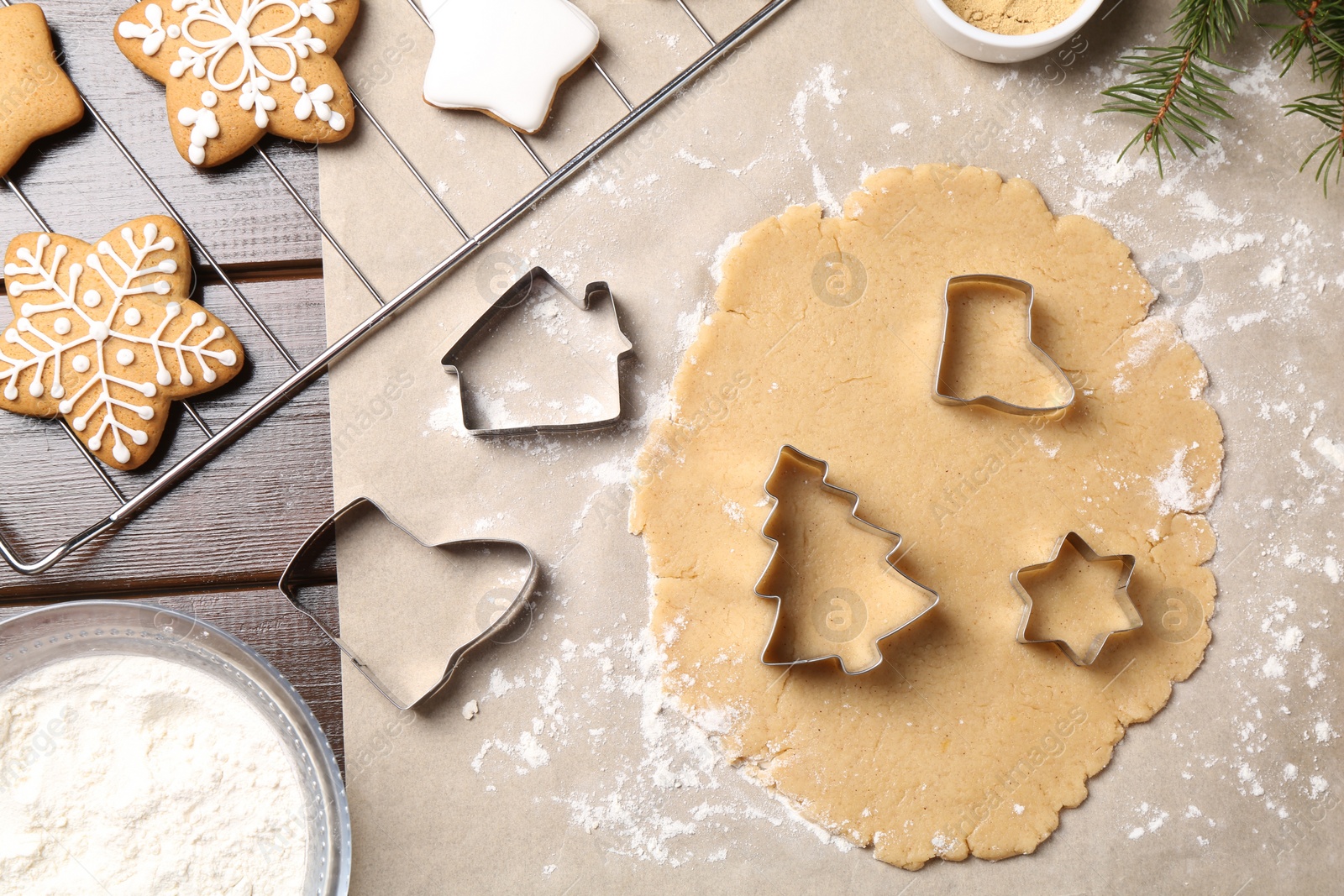 Photo of Making Christmas cookies. Flat lay composition with cutters and raw dough on wooden table