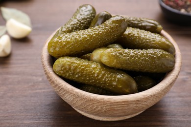 Photo of Bowl of pickled cucumbers on wooden table, closeup
