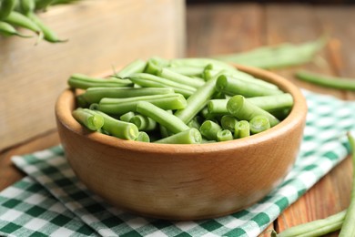 Photo of Fresh green beans in bowl on wooden table, closeup