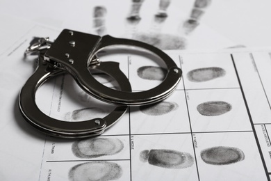 Photo of Police handcuffs and criminal fingerprints card, closeup