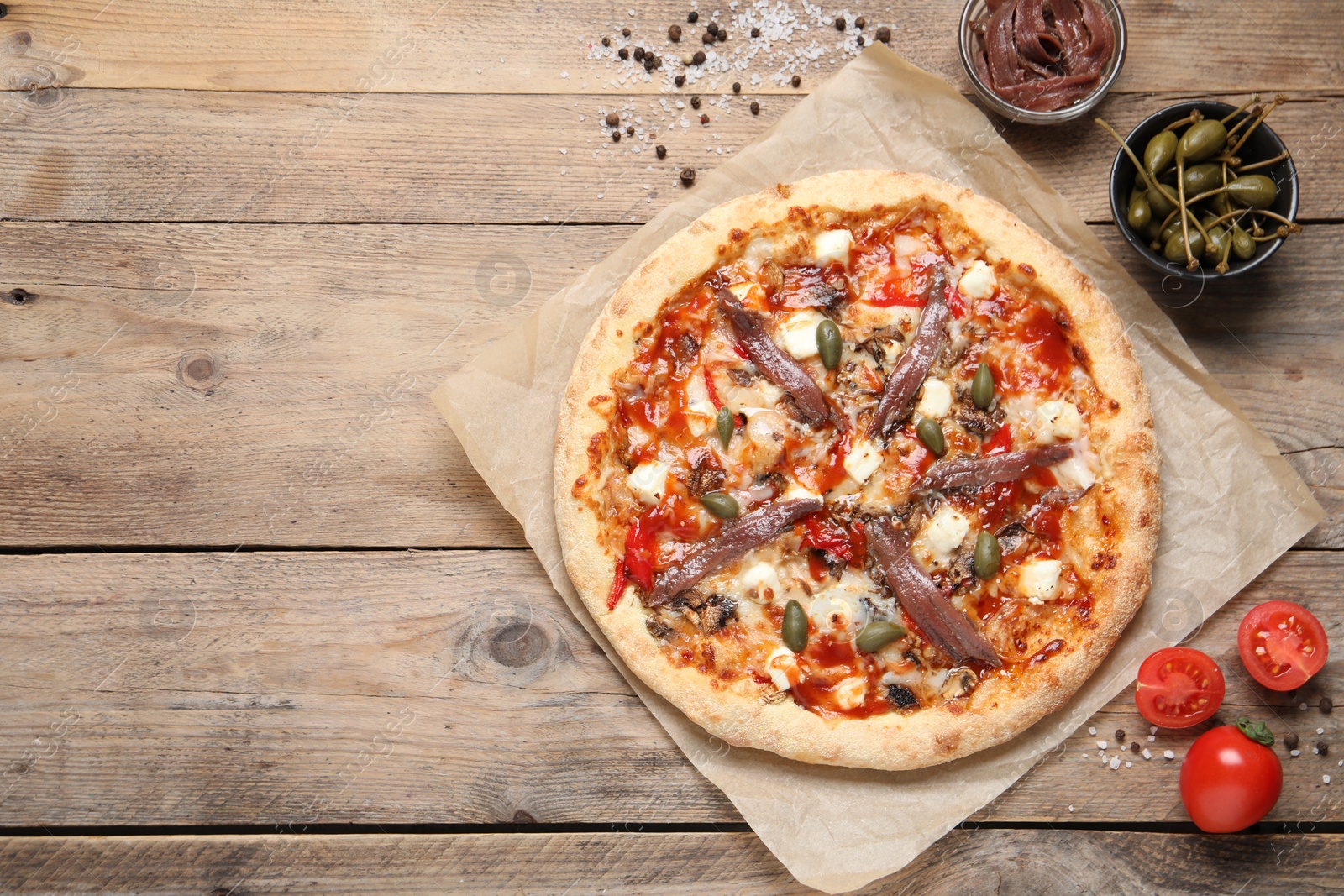 Photo of Tasty pizza with anchovies and ingredients on wooden table, flat lay. Space for text