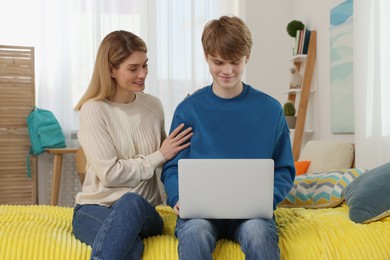 Happy mother and her teenage son with laptop at home