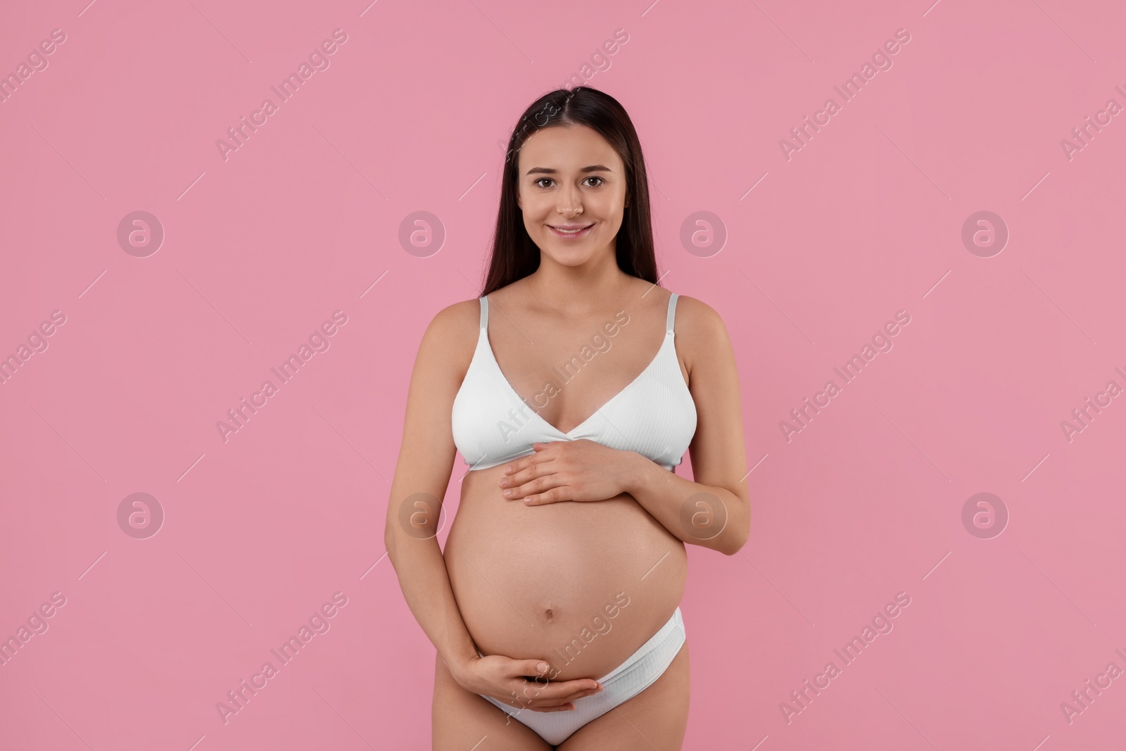 Photo of Happy pregnant woman in stylish comfortable underwear on pink background