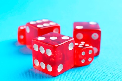 Photo of Many red game dices on light blue background, closeup