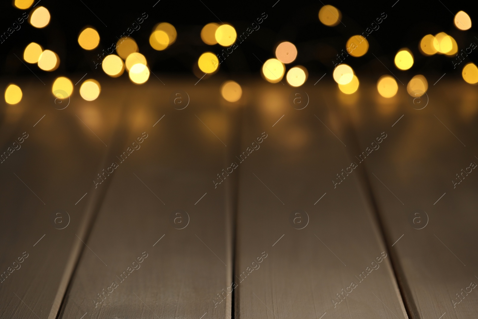 Photo of Blurred view of festive lights on wooden table, space for text