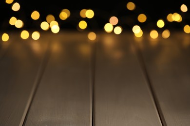 Photo of Blurred view of festive lights on wooden table, space for text