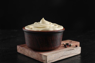 Fresh mayonnaise sauce in bowl on black table, closeup