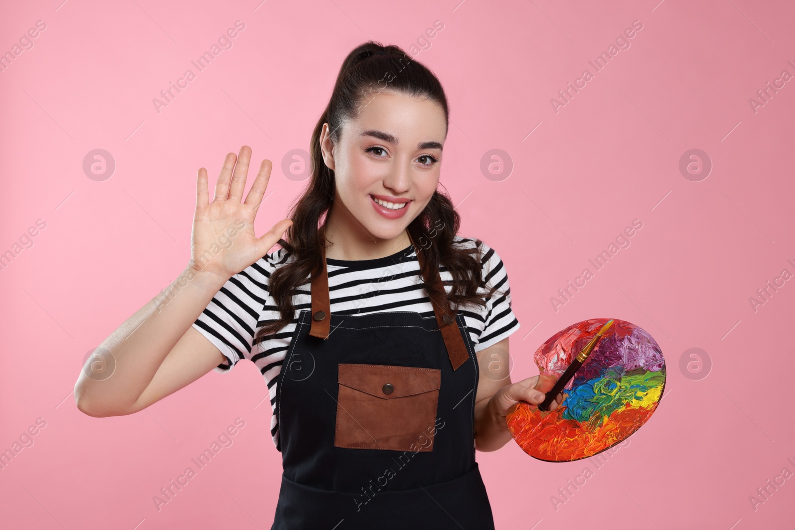 Photo of Woman with paint palette on pink background. Young artist