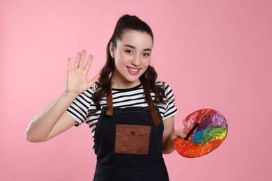 Woman with paint palette on pink background. Young artist