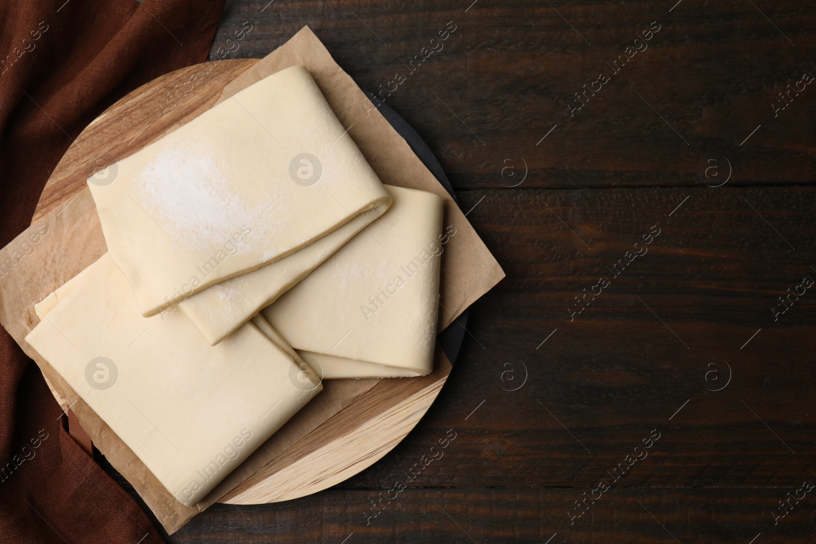 Photo of Raw puff pastry dough on wooden table, top view. Space for text