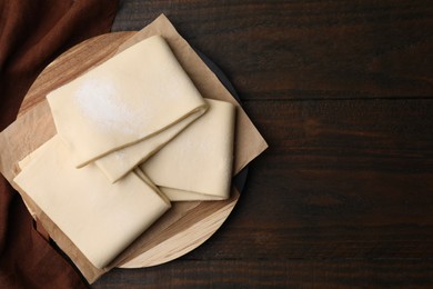 Raw puff pastry dough on wooden table, top view. Space for text