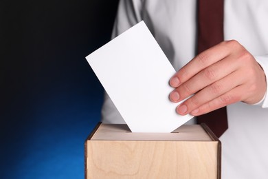 Photo of Man putting his vote into ballot box on dark blue background, closeup. Space for text