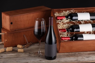 Box with wine bottles, glass, corks and corkscrew on wooden table